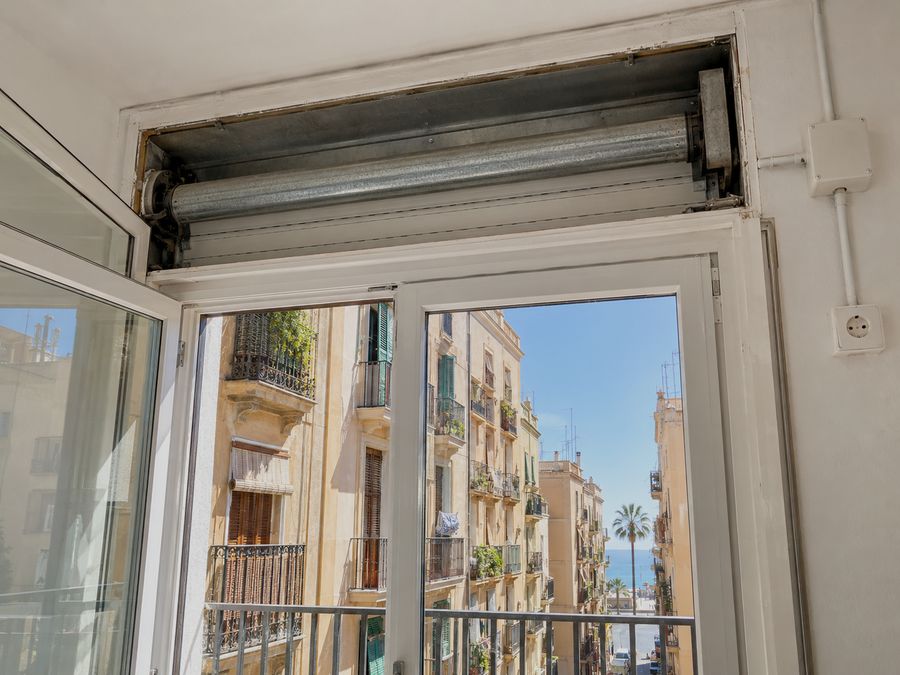 Cajón de persiana abierto desde dentro de la habitación, con el enchufe al lado