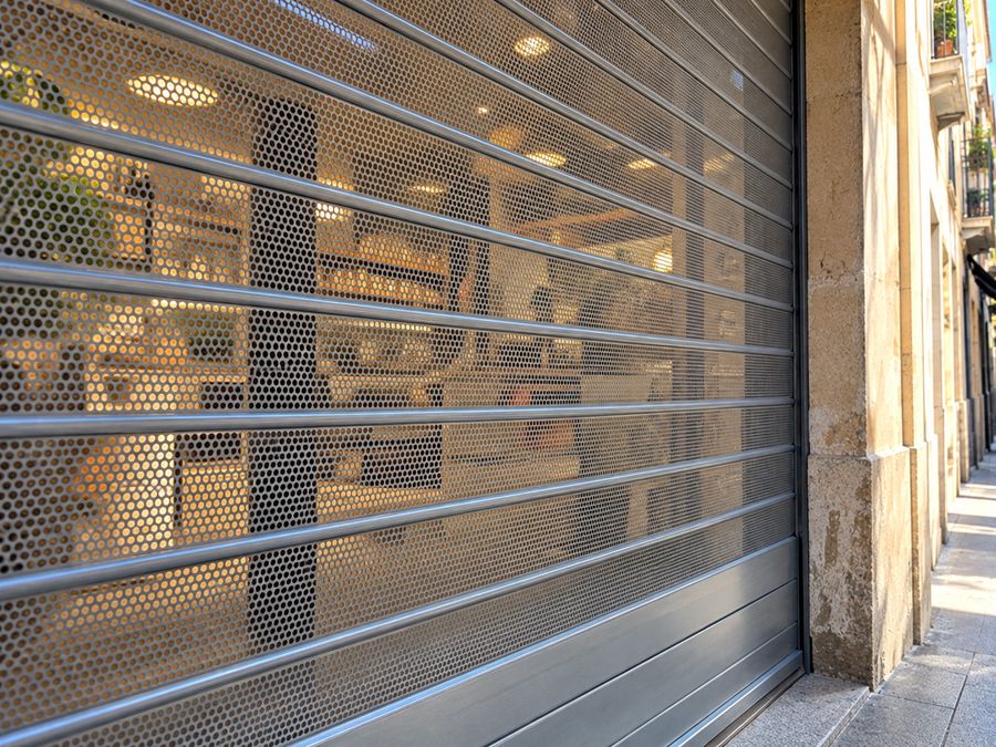 Lama microperforada de un cierre metálico bajado que deja ver el interior de una tienda
