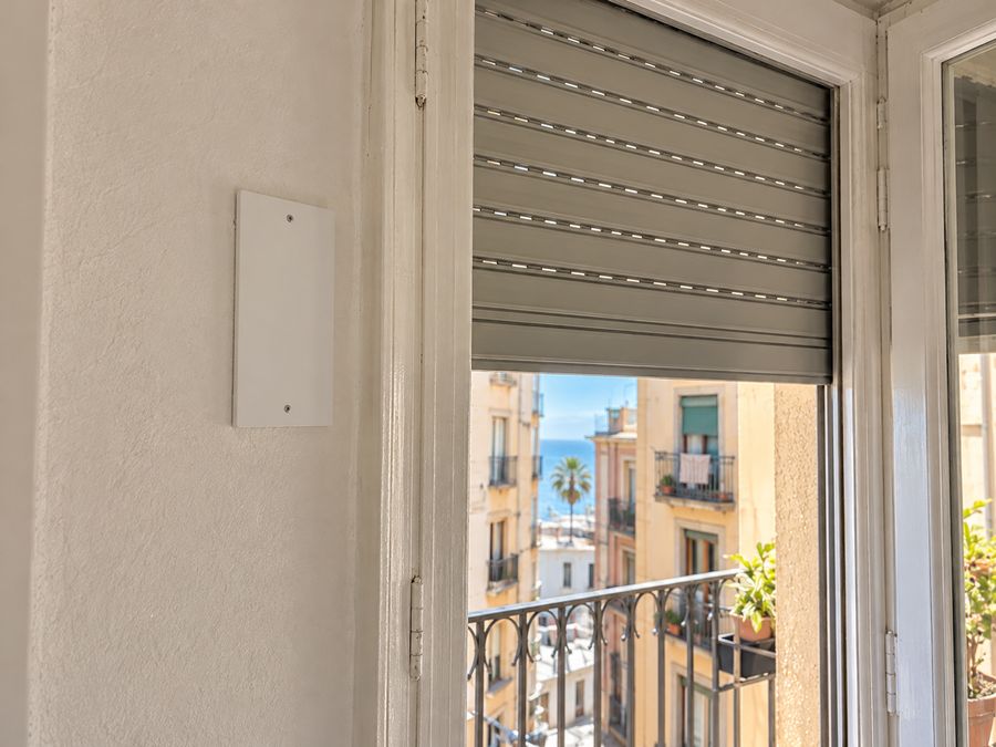 Placa lisa tapando el hueco del antiguo recogedor de cinta, junto a la ventana de una persiana ya motorizada
